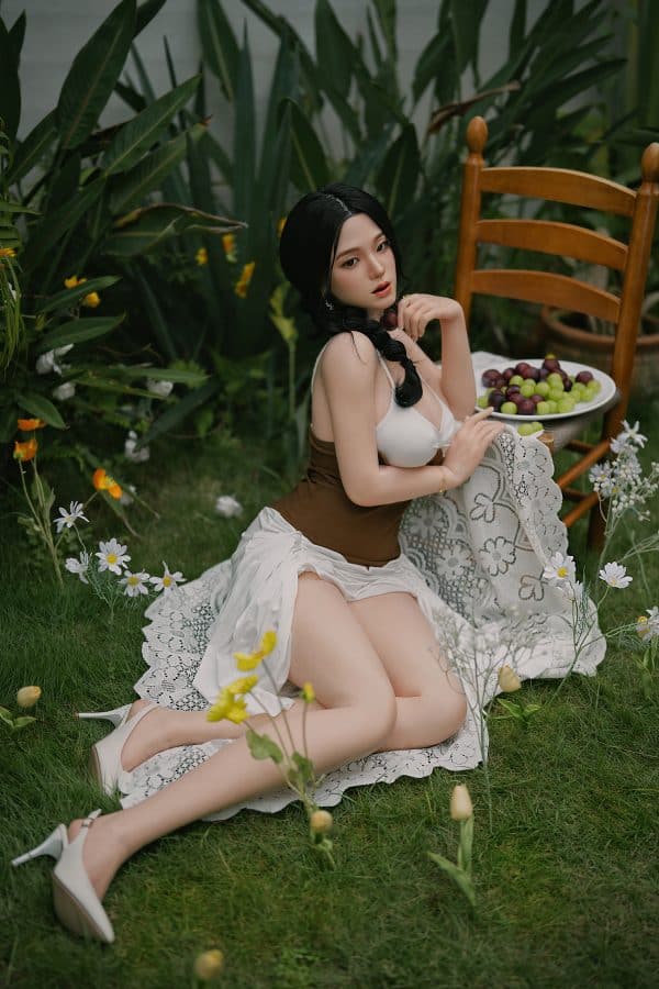 Luxurious love doll posing outdoors in a garden scene for realistic intimacy experience.