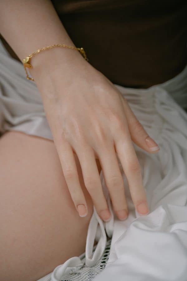 Silicone sex doll hand with detailed nails and gold bracelet, realistic adult intimacy accessory.