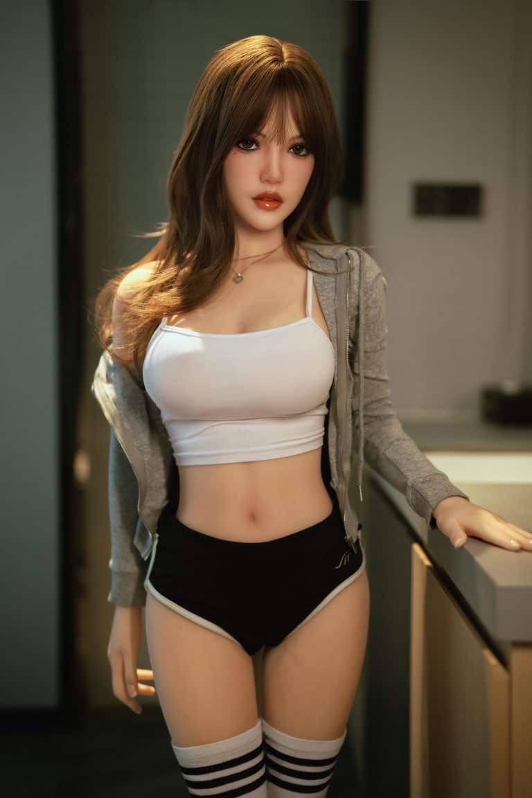 Realistic love doll modeled after a young woman in casual athletic wear for bedroom or intimate settings.