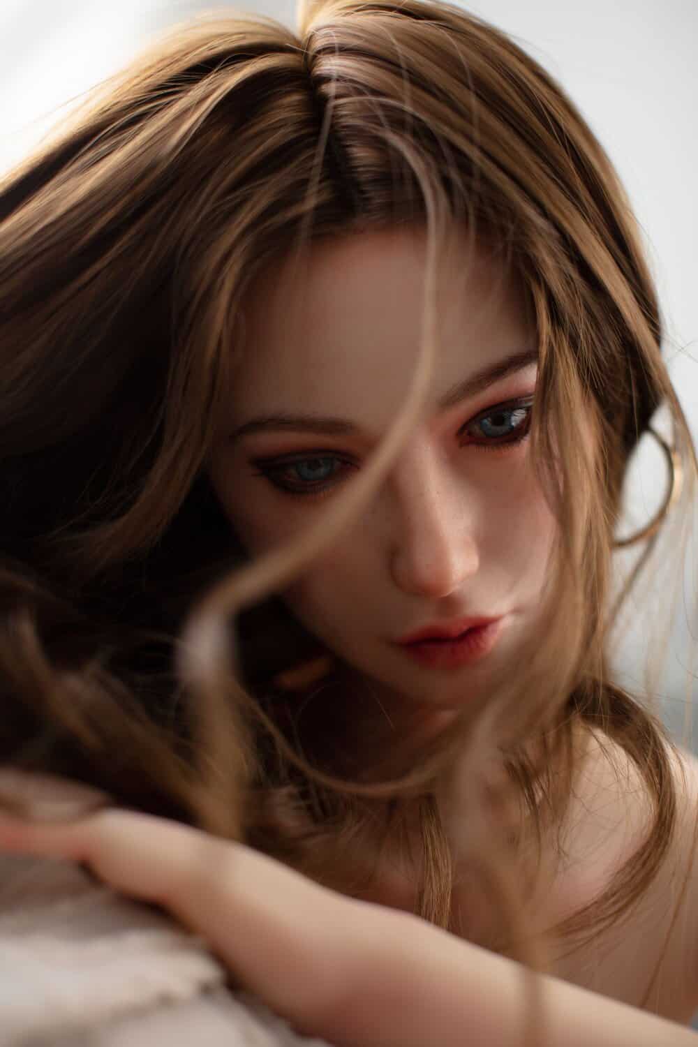 Realistic female doll head with brown hair and blue eyes for adult novelty products.