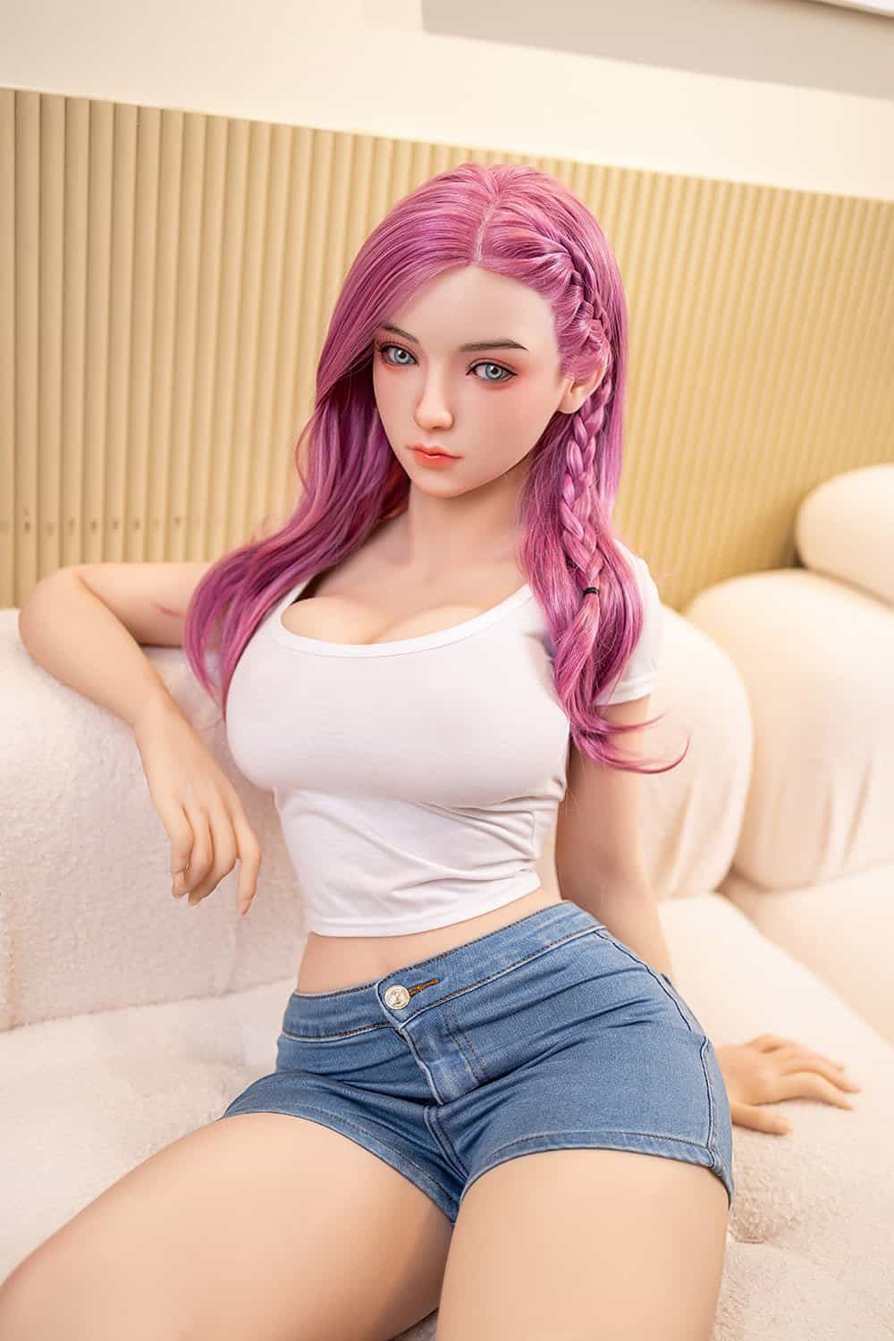 Realistic sex doll with pink hair relaxing on a cream-colored couch, showcasing detailed facial features and lifelike appearance.