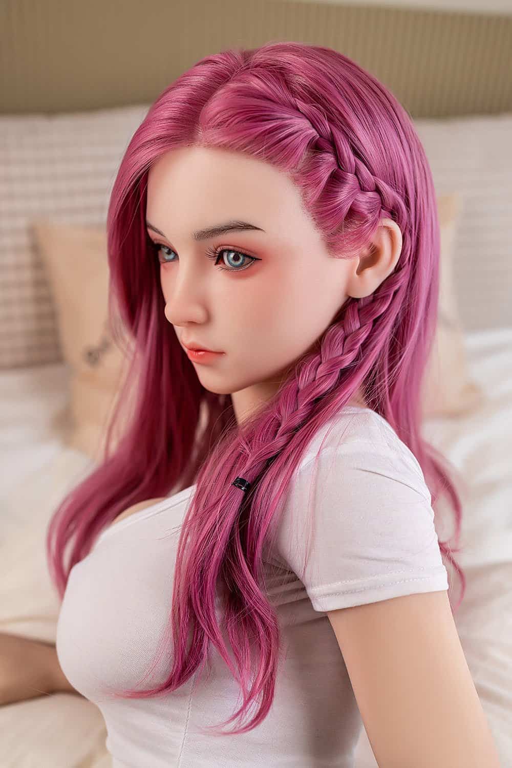 Pink-haired realistic sex doll with braided hair and blue eyes in bedroom.