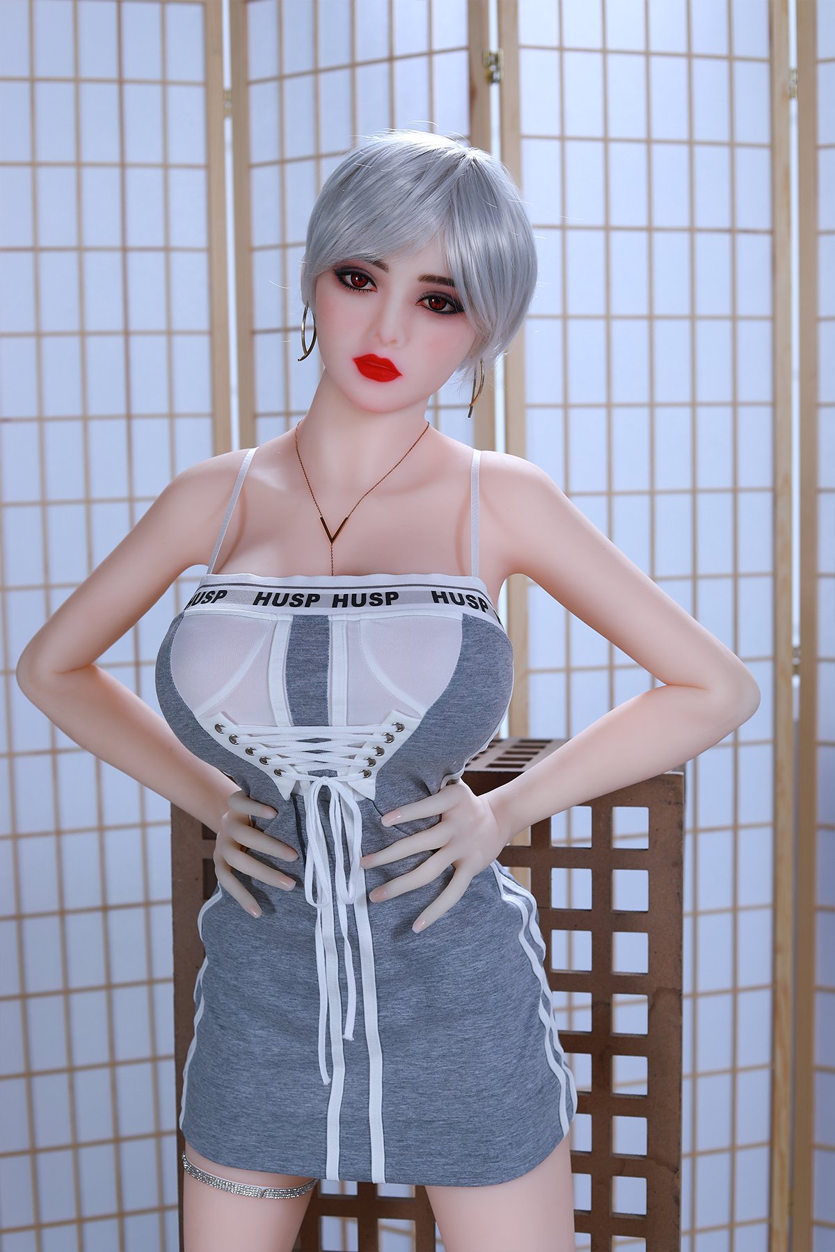Realistic sex doll with short silver hair and bold makeup in a modern indoor setting.