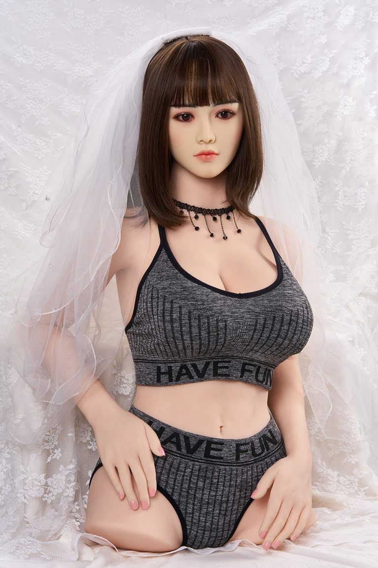 Realistic sex doll with brown hair dressed in casual athletic wear and wedding veil, posing on lace background.