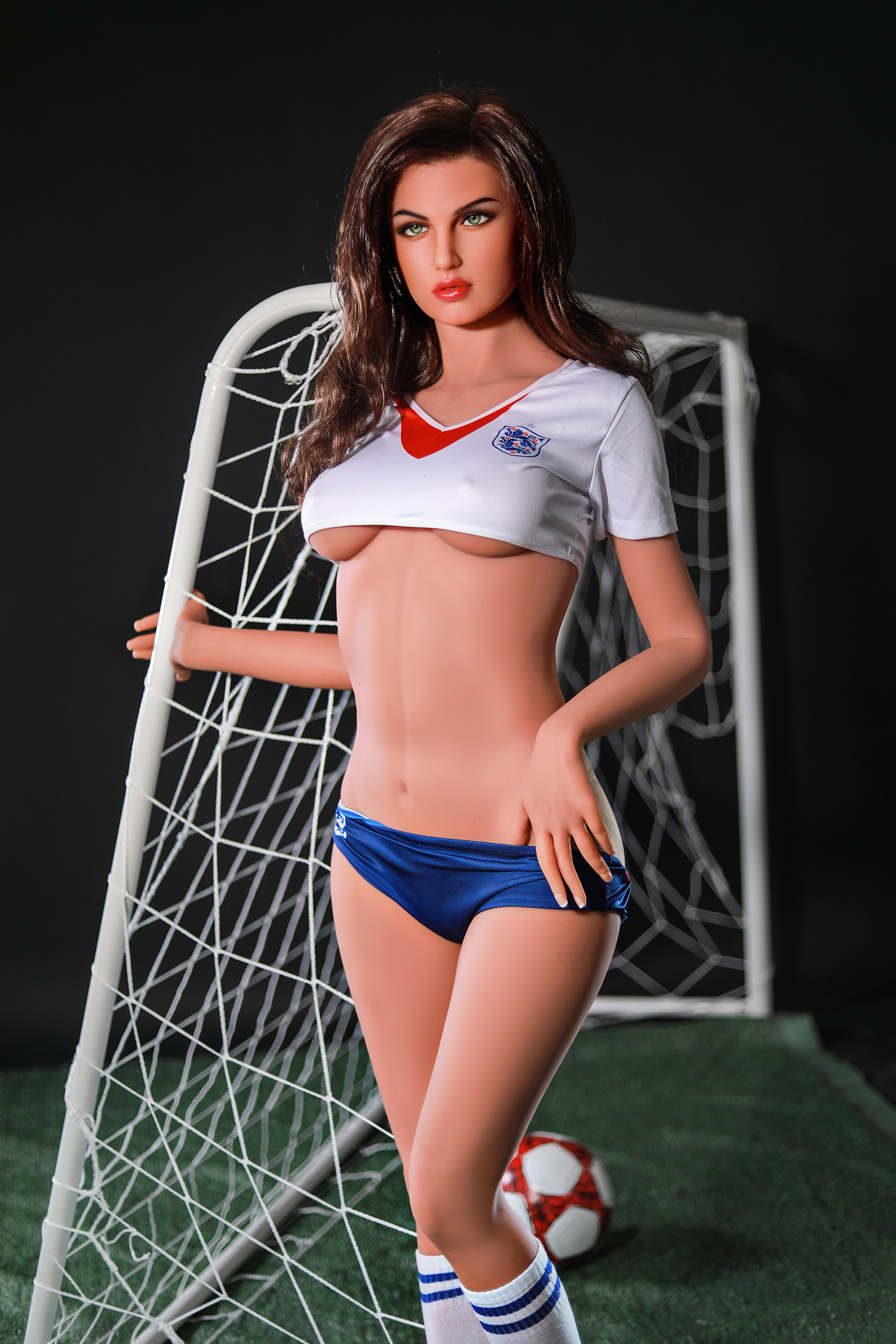 Sexy female doll in sports jersey and shorts with soccer ball on field.