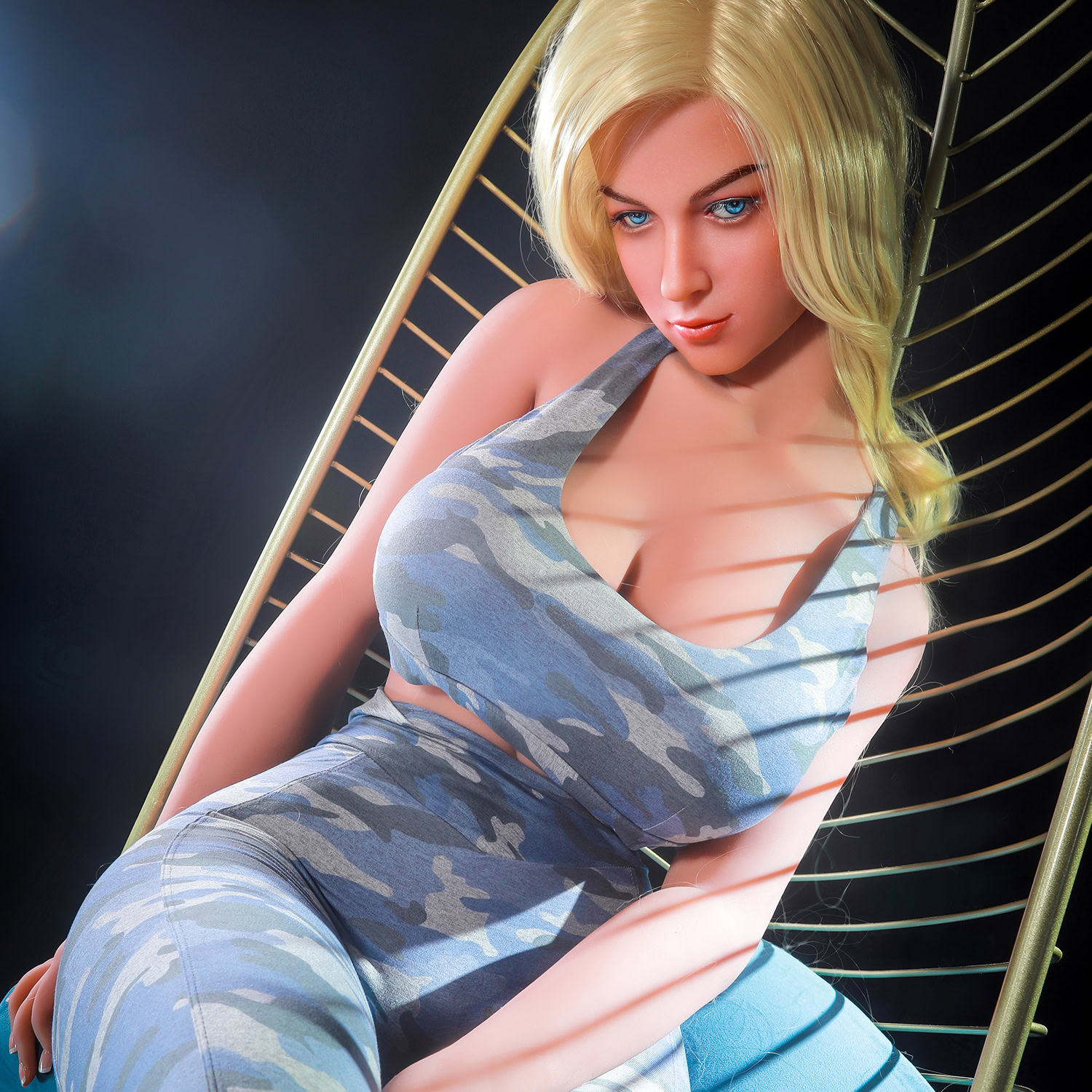 Seductive realistic female silicone doll with blonde hair and blue eyes relaxing in modern chair.