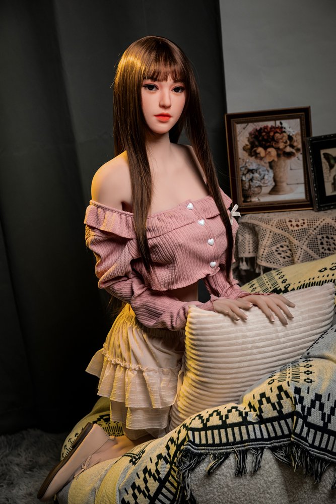 Realistic female doll posing on a cozy sofa, detailed face and long brown hair, perfect for adult companionship.