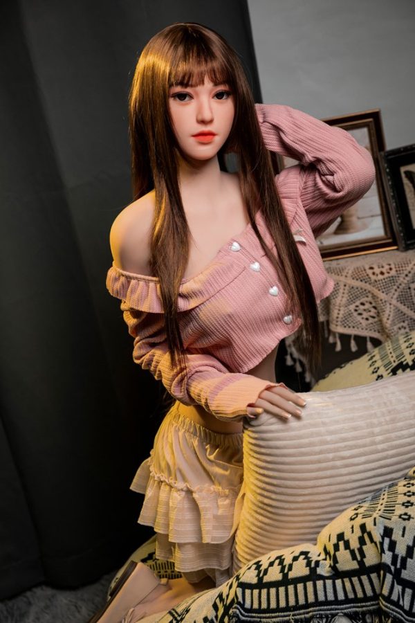 Realistic love doll with long brown hair and detailed facial features in a cozy home setting.