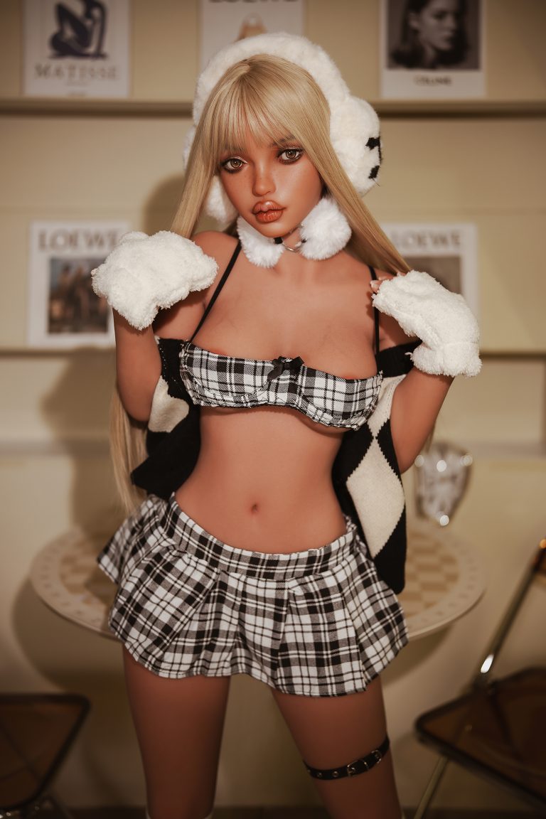 Cute anime-inspired doll in playful plaid outfit with fluffy earmuffs and gloves, posing indoors for photo.
