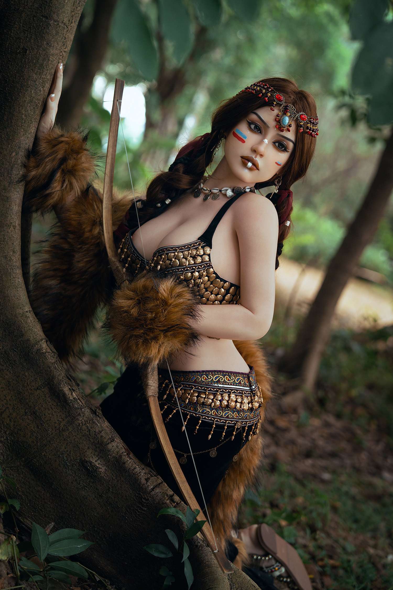Vibrant fantasy doll in tribal warrior costume holding a bow in a forest setting with lush greenery.