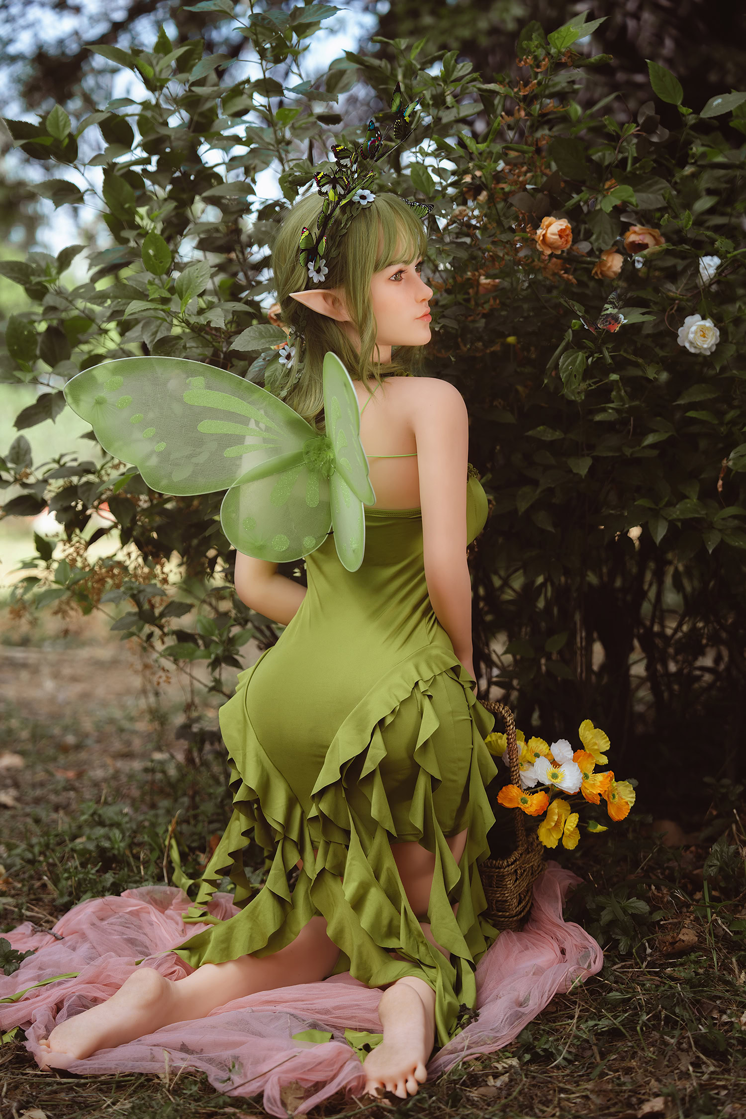 Fairy costume with green dress, fairy wings, elf ears, and floral headpiece in enchanted forest setting.