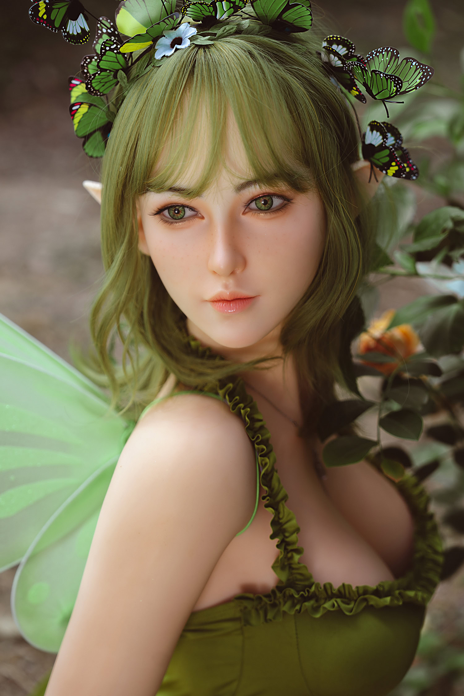 Butterfly fairy doll with green hair and botanical costume in a garden setting.