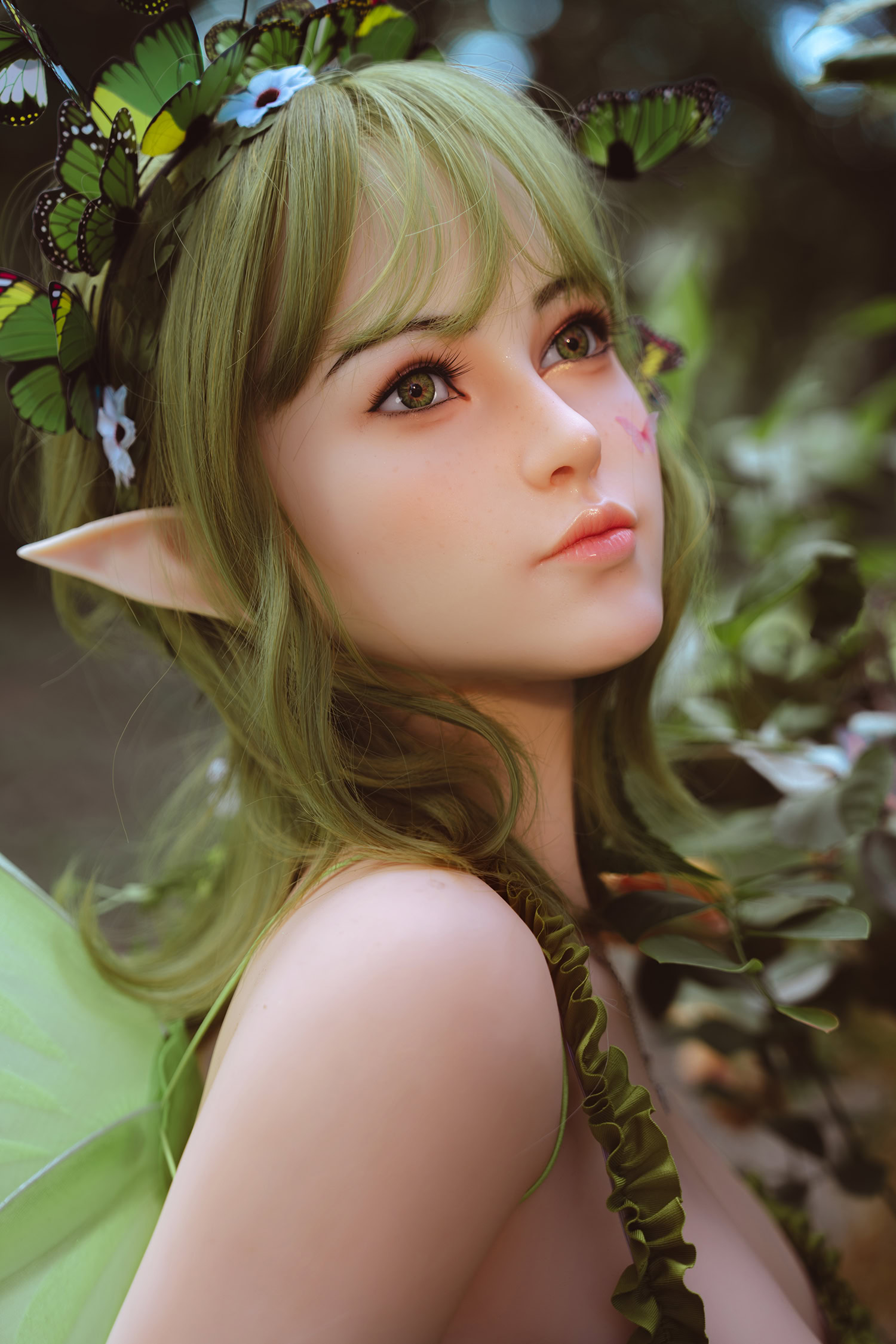 Delicate fantasy elf doll with butterfly wings and greenery, close-up portrait in nature setting.