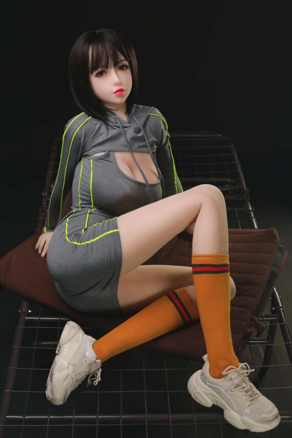 Realistic female doll sitting on bed in sportswear.