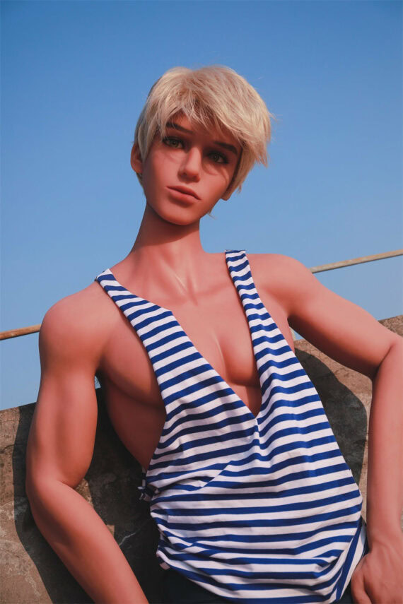Realistic female love doll with short blonde hair, wearing a striped tank top, outdoors against a blue sky.