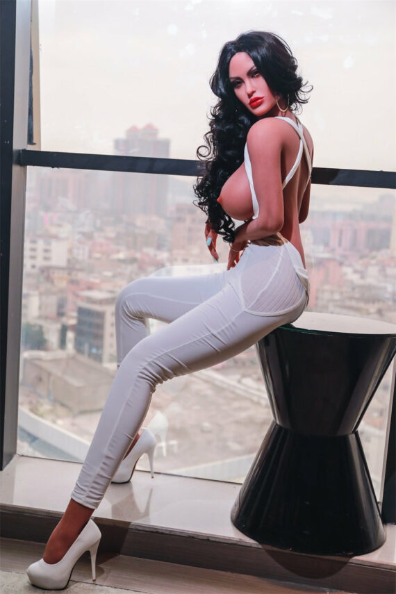 Seductive doll female sex figure in stylish dress with high heels by large window with city view.