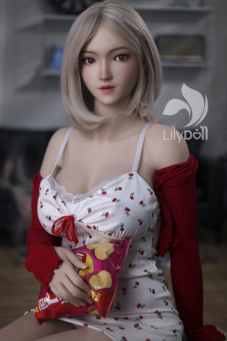 Realistic female love doll with blonde hair and floral dress holding potato chips.