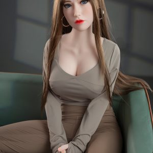 Realistic sex doll sitting on green sofa, detailed face with blue eyes, long brown hair, wearing beige outfit.