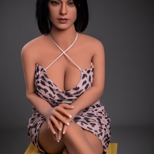 Realistic female doll wearing leopard print dress, sitting on a wooden stool, showcasing detailed craftsmanship.