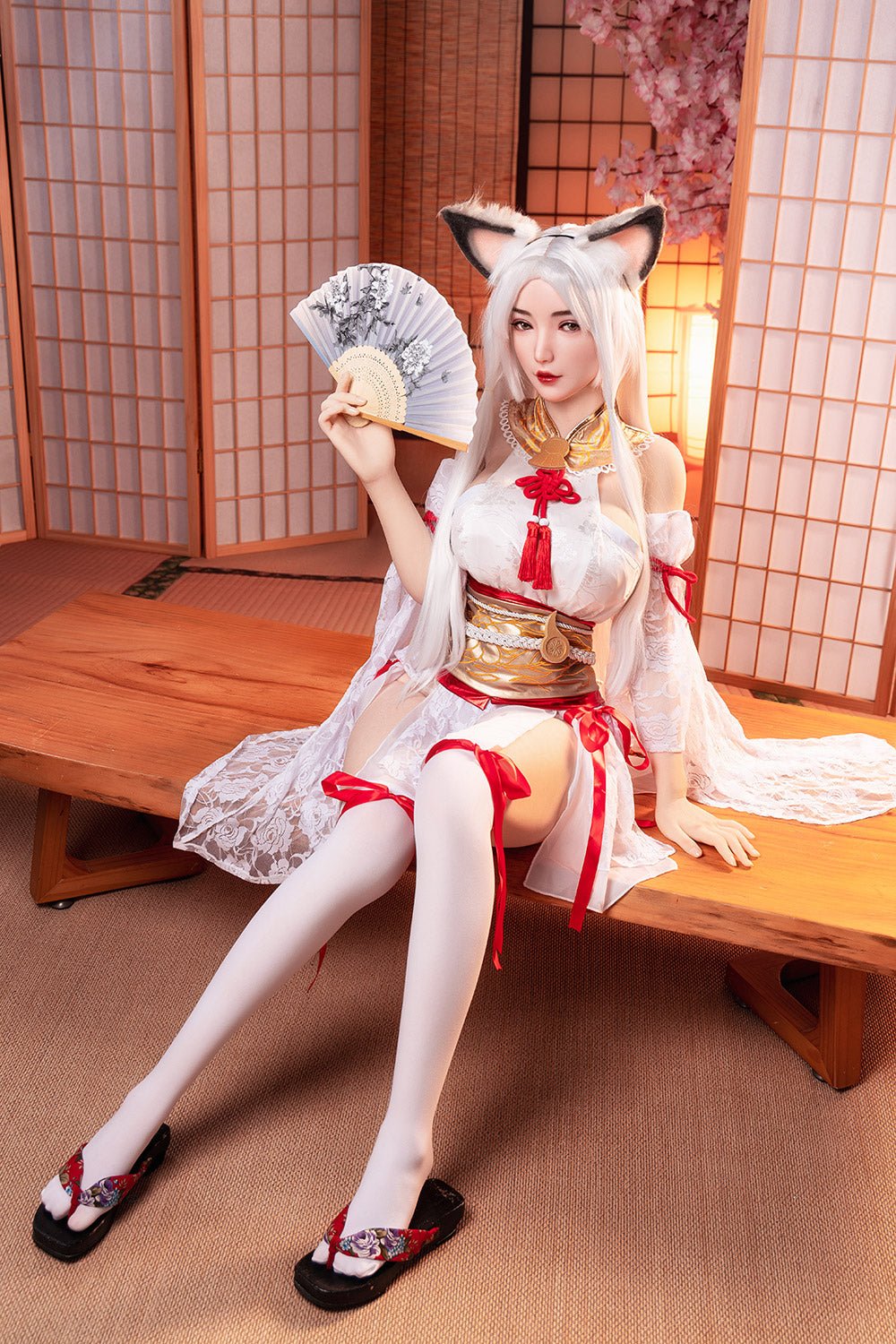 Deluxe anime-style sex doll dressed in traditional Japanese kimono, with fox ears and long silver hair, sitting on a wooden table in a Japanese-inspired room.