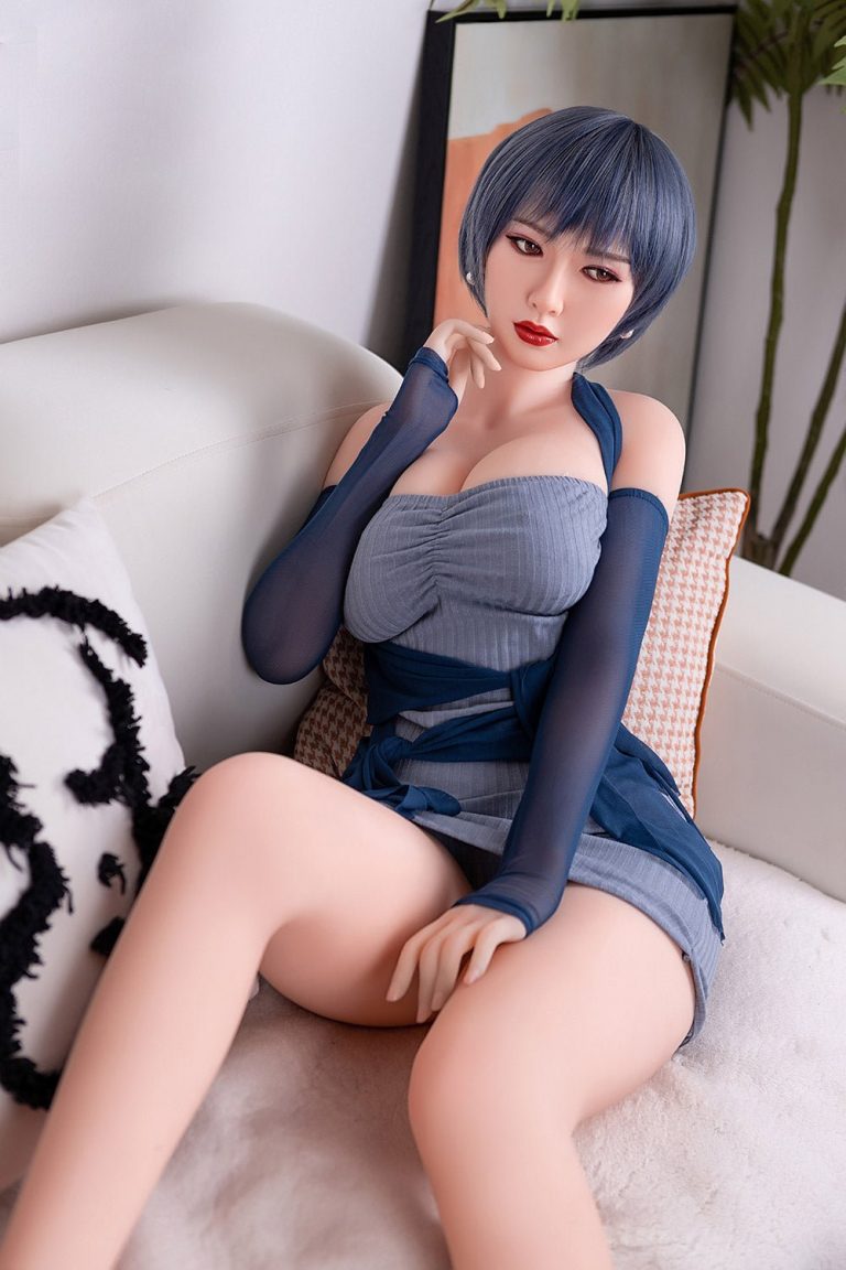 Realistic female love doll sitting on sofa, short blue hair, seductive pose, high-quality sex doll for adults, Seducedoll product image.