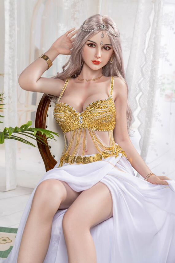 Seduction doll wearing a gold embellished top and flowing white skirt, sitting elegantly indoors.