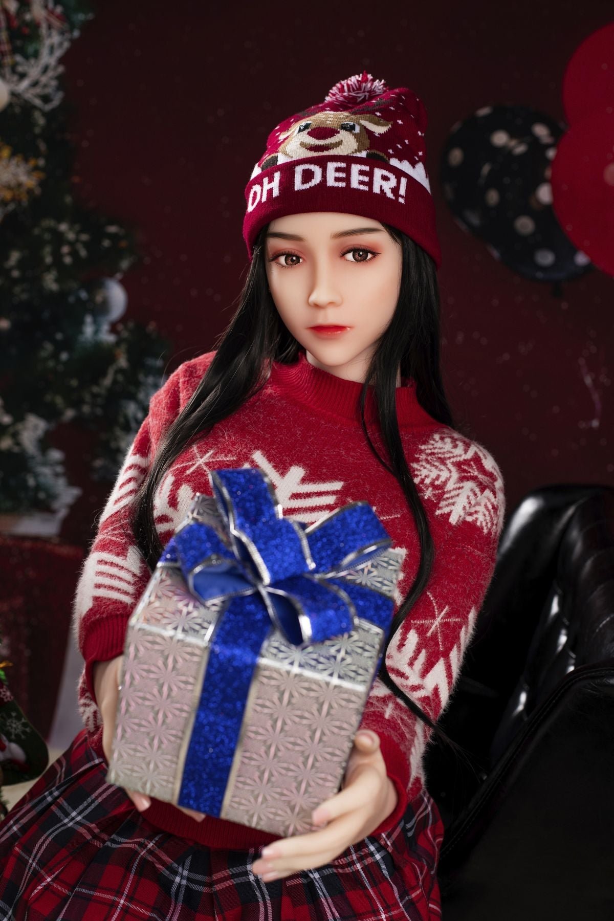 Cute woman in Christmas sweater holding gift box with festive background.