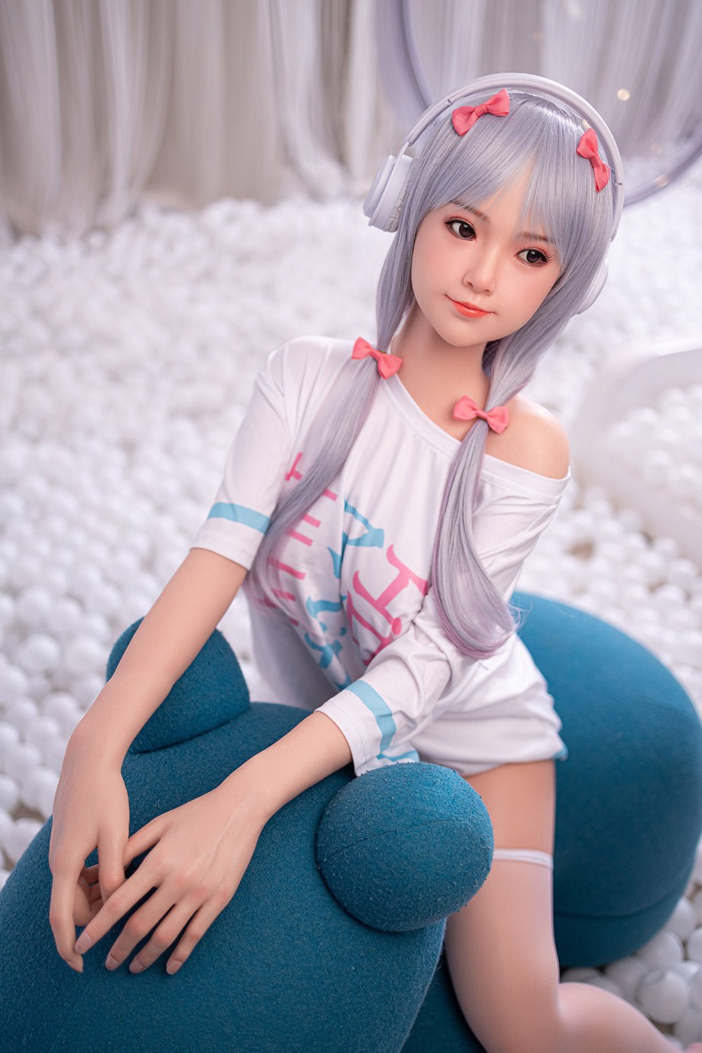 Silicone sex doll with anime-inspired features, long silver hair, pink bows, and headphone accessories.