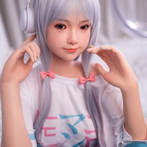 Cute anime-style doll with silver hair, pink bows, wearing headphones, and a casual colorful t-shirt.