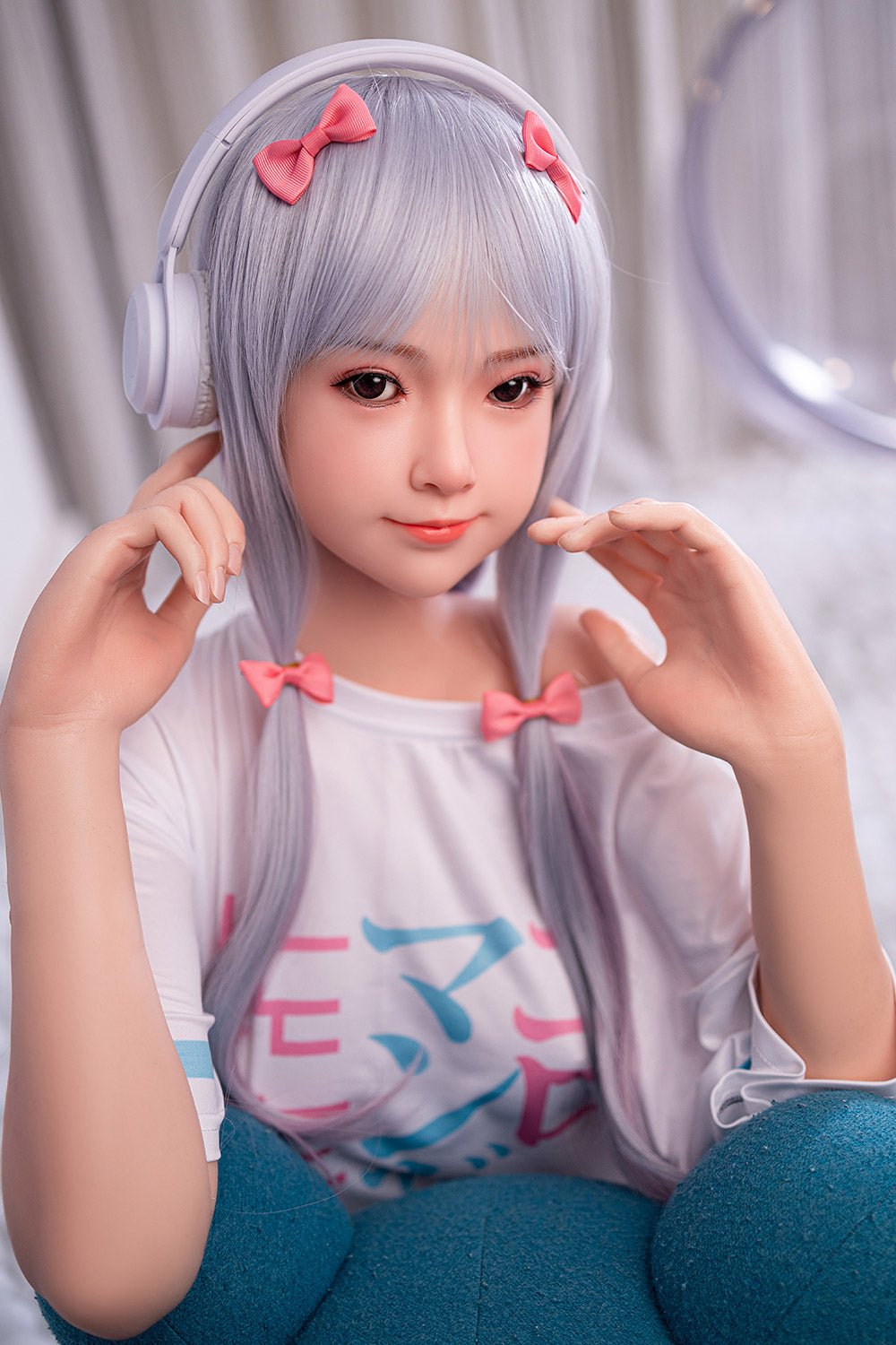 Cute anime-style doll with silver hair, pink bows, wearing headphones, and a casual colorful t-shirt.