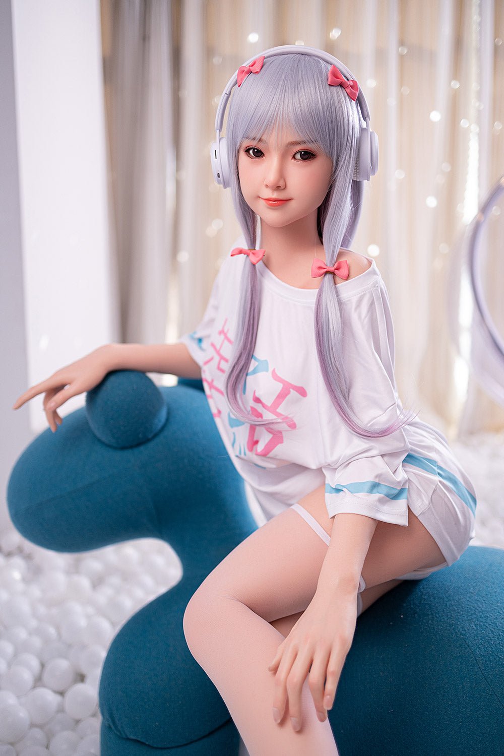 Silicone sex doll with anime-style face, purple hair, and headphones, posing on blue sofa in casual outfit.