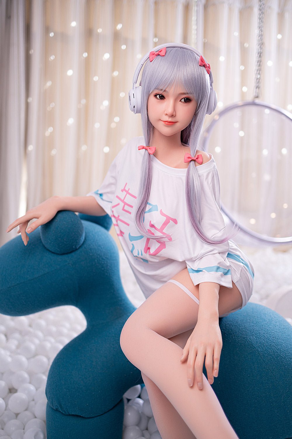 Doll wearing headphones and casual pajamas relaxing on a modern blue sofa in a cozy room with soft lighting.