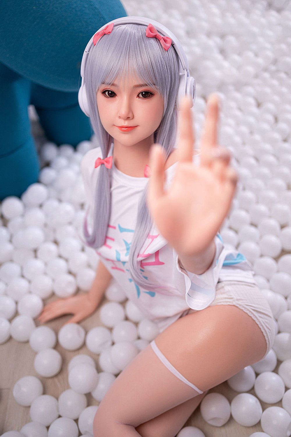 Cute anime-style doll with purple hair and headphones, posing in a ball pit with playful expression.