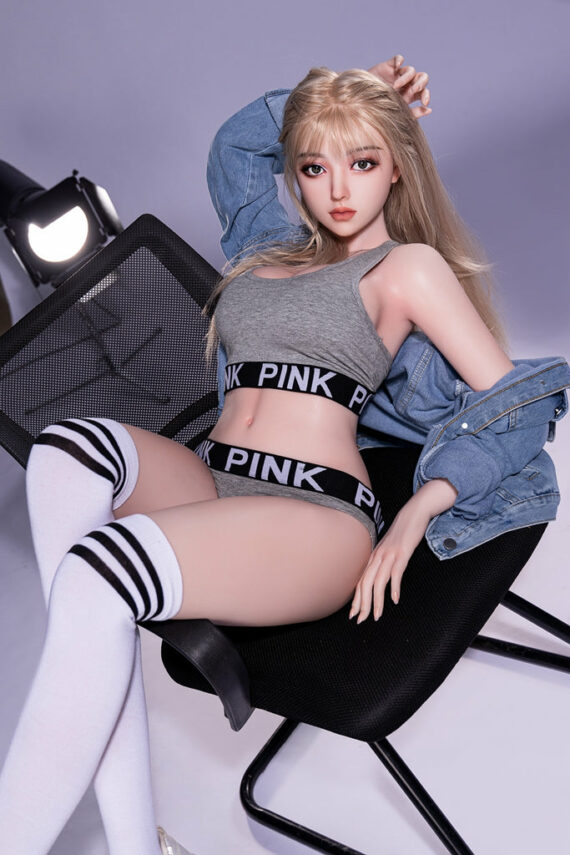 Realistic love doll sitting on chair with sporty lingerie, blonde hair, gray tank top, and thigh-high socks.