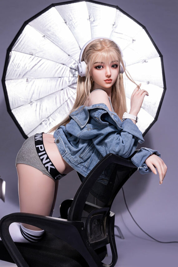 Sexy female doll with blonde hair posing with professional photography lighting equipment.