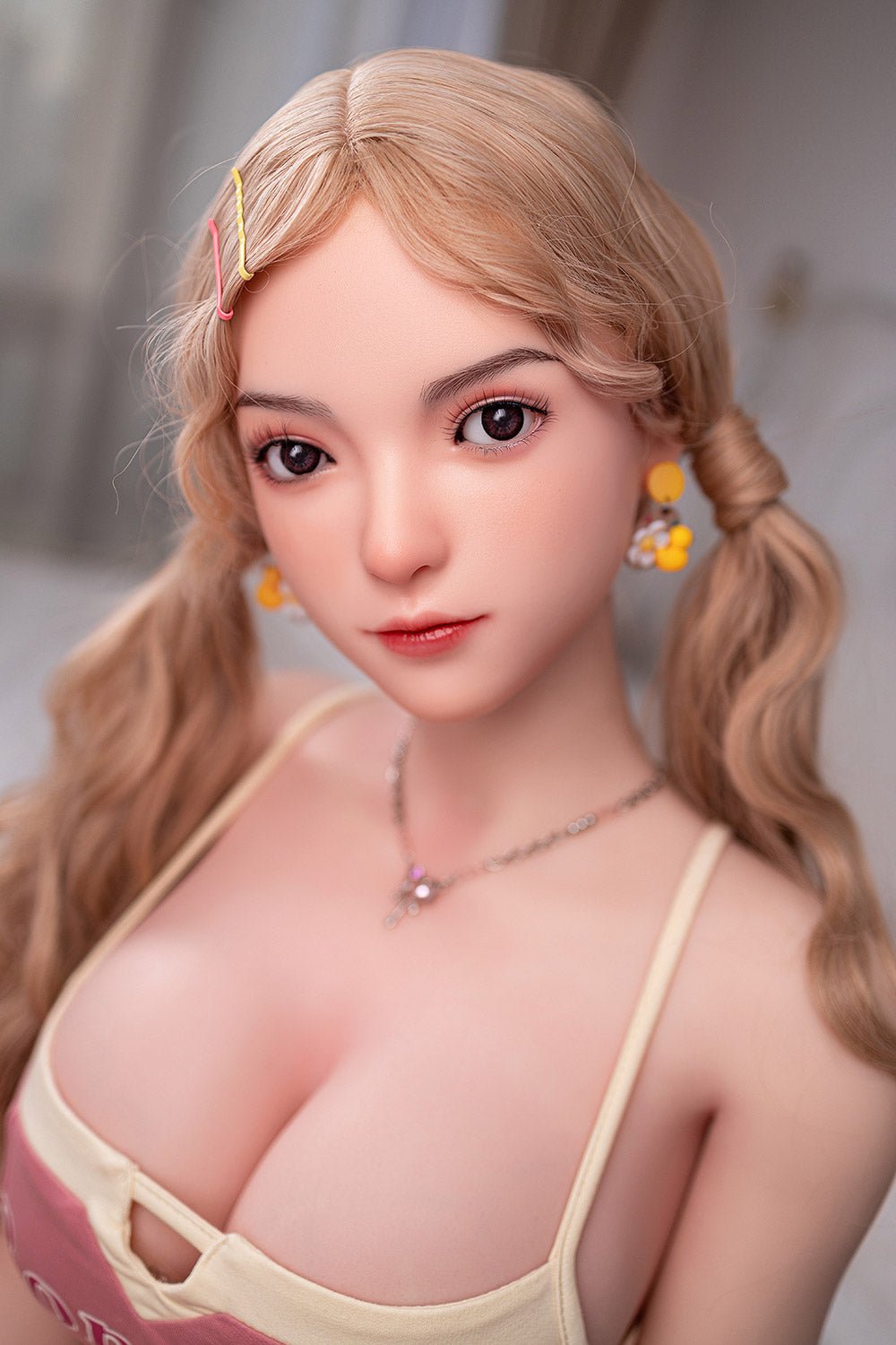 Realistic sex doll with detailed facial features and blonde hair, dressed in a pink top.