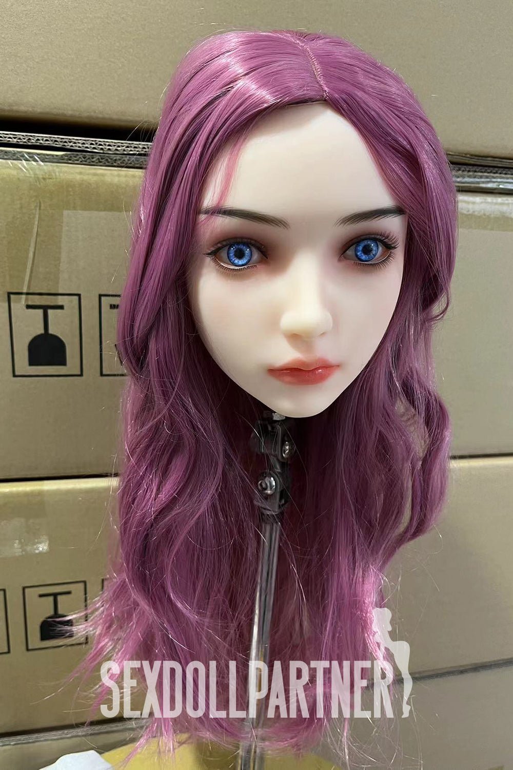 Pink-haired sex doll head with realistic features and blue eyes for adult companionship.